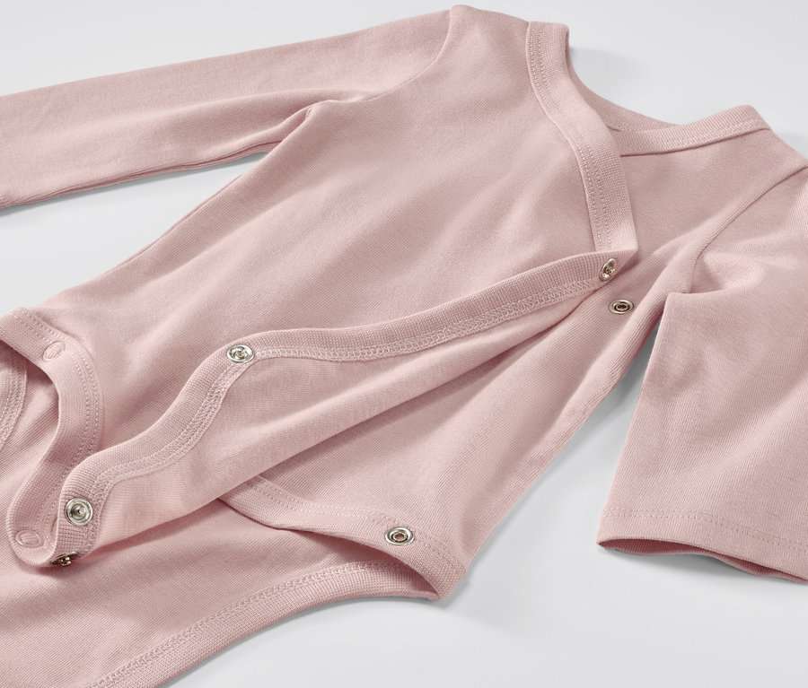 Egy rózsaszín, hosszú ujjú, patentos, állítható hosszúságú kisgyerek body közelről.