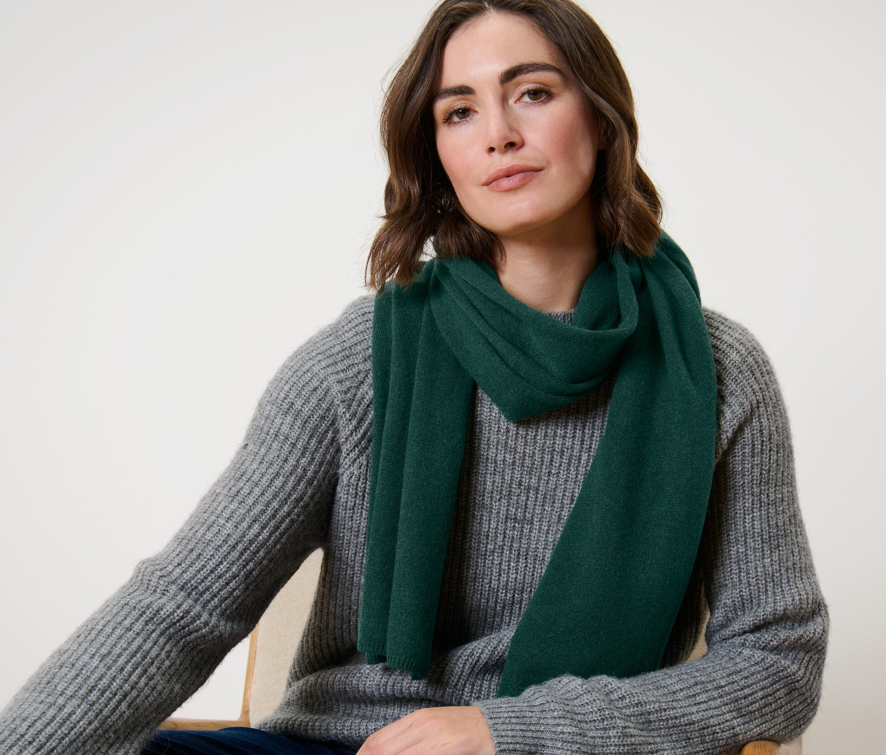 Egy nő ül, és egy sötétzöld kasmír kötött sálat visel.