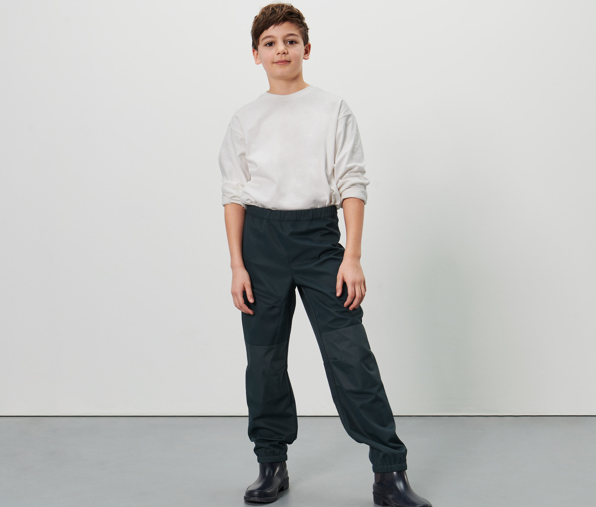 Egy fiú pózol sötétkék gyerek softshell nadrágban.