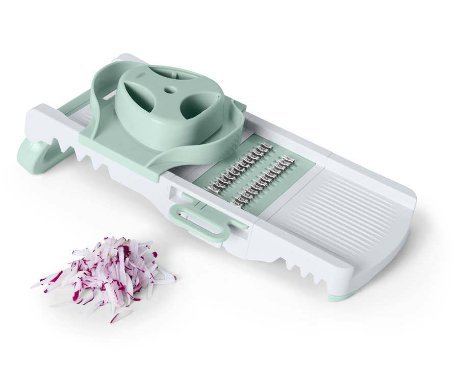 Egy fehér zöldségszeletelő világoszöld díszítéssel a vágott vöröshagyma mellett.