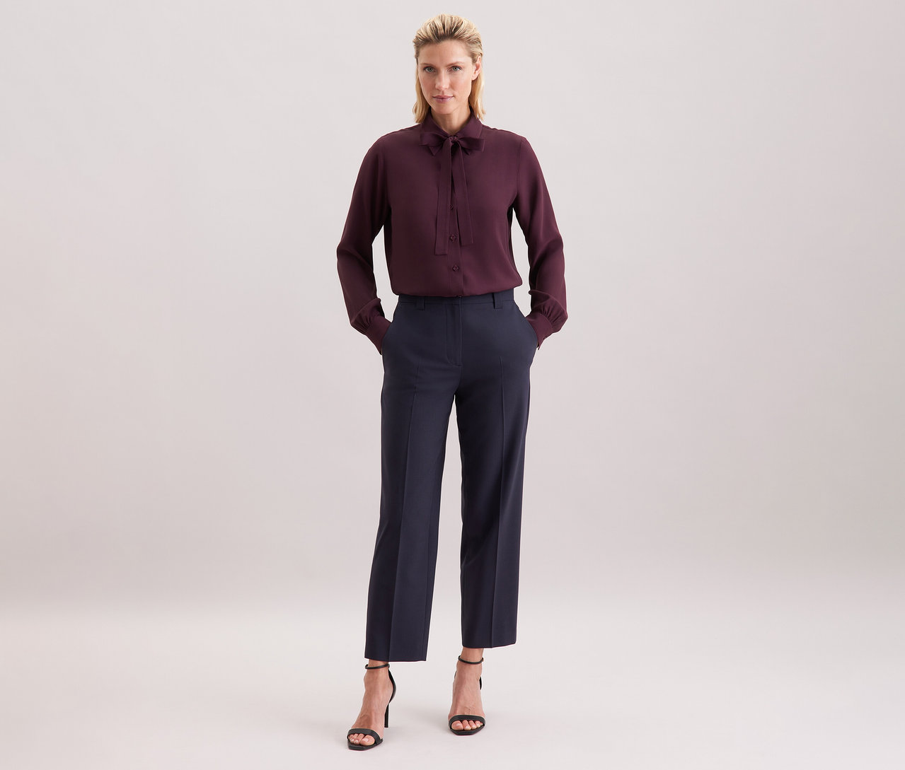 Nő viszkóz Seidensticker sifon blúzban, sötét nadrágban és fekete szandálban.