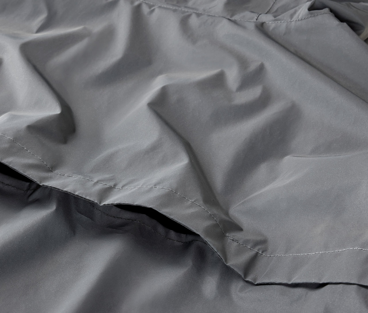 Egy szürke, fényvisszaverő sportkabát részlete.