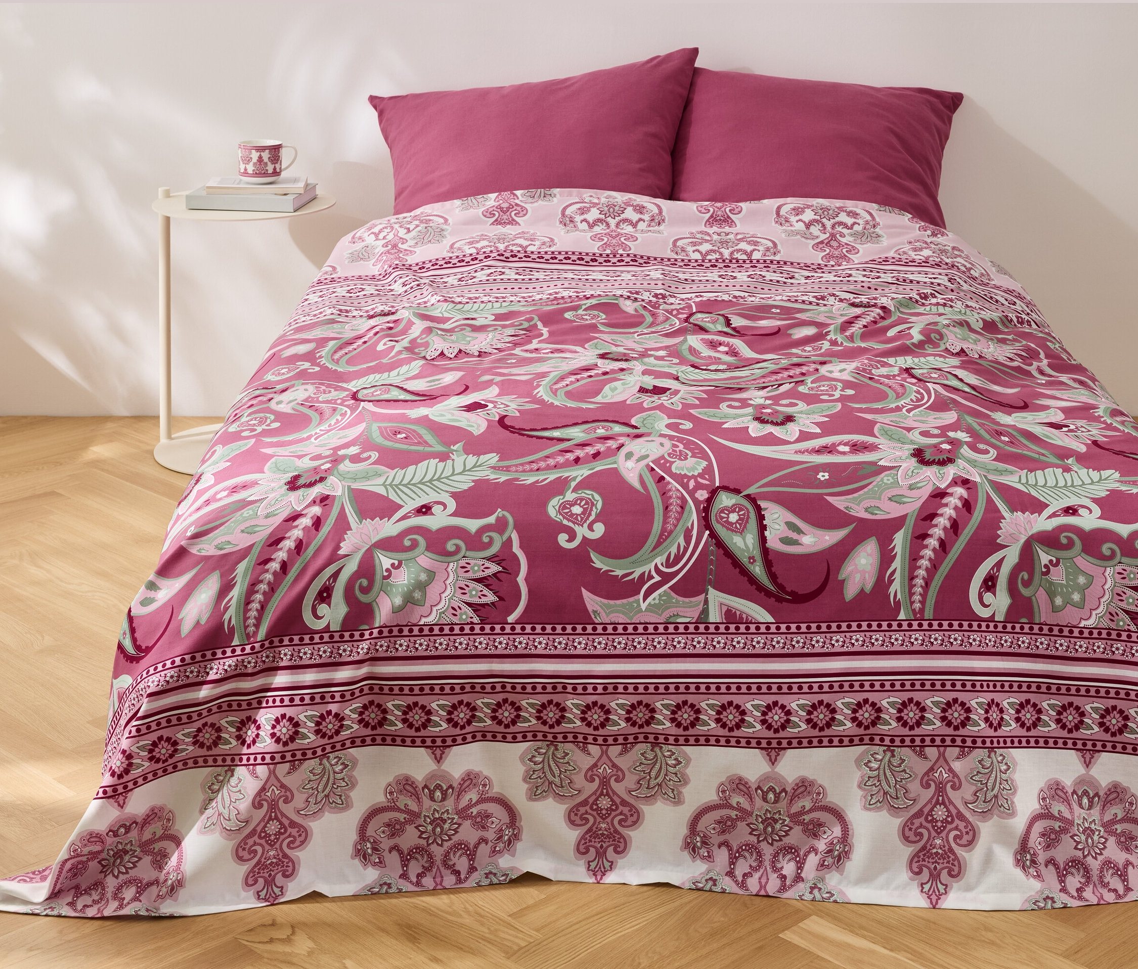 Egy ágy virágmintás renforcé-Multifunktions-Überwurf ágyneművel és két párnával.