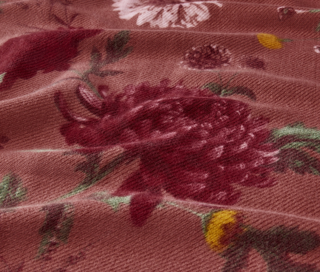 Közeli kép egy rózsaszín és zöld árnyalatú virágmintás szövetről.