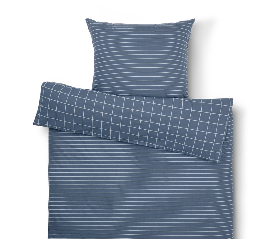Kék ágynemű szett fehér csíkokkal és kockákkal.