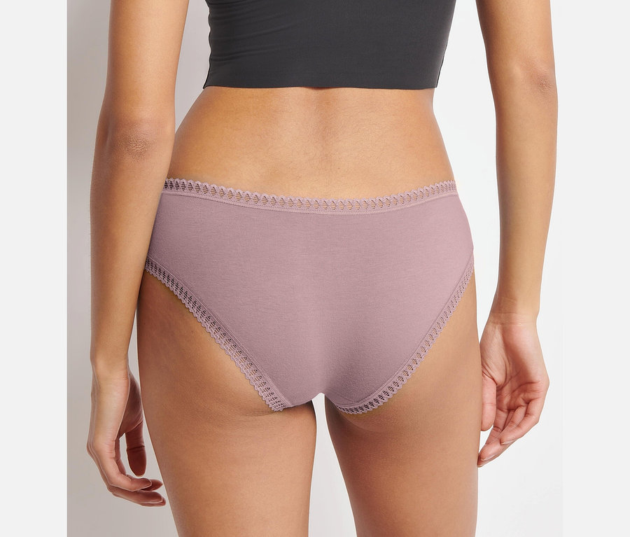 Közeli kép egy fekete felsőt és rózsaszín Sloggi Go Crush hipster alsót viselő nőről hátulról.