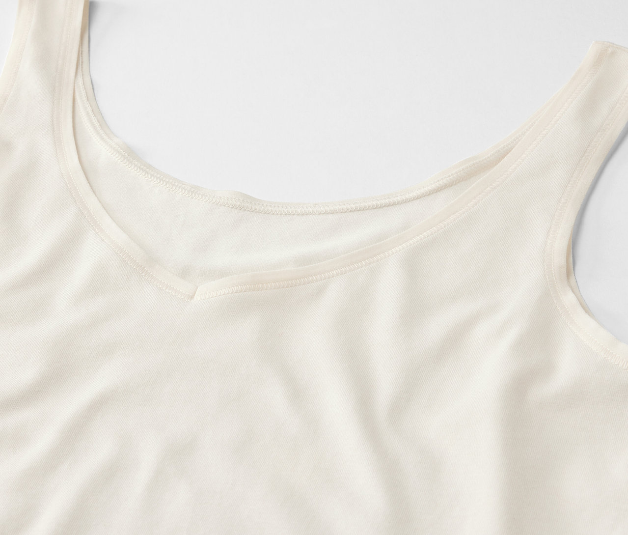 Egy krémszínű, V-nyakú trikó részlete.