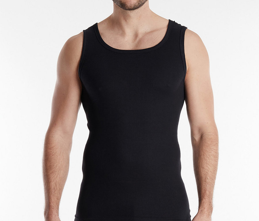 A göndör hajú férfi fekete trikót és boxeralsót visel fehér háttér előtt.