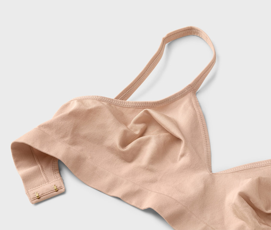 Egy testszínű, vékony pántos, arany kapcsokkal ellátott melltartó közeli képe.