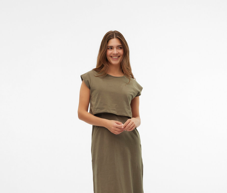 Nő visel khaki ruhát és krémszínű Mary Jane cipőt fehér háttér előtt.