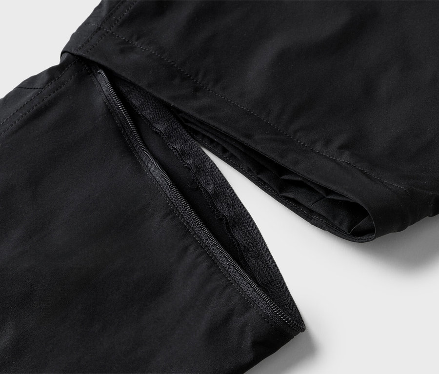 Egy fekete nadrág részletgazdag képe, nyitott cipzárral.