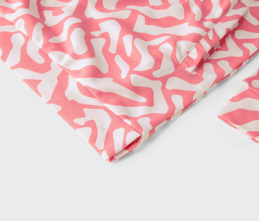 Egy ruhadarab közeli képe rózsaszín és fehér absztrakt mintával.