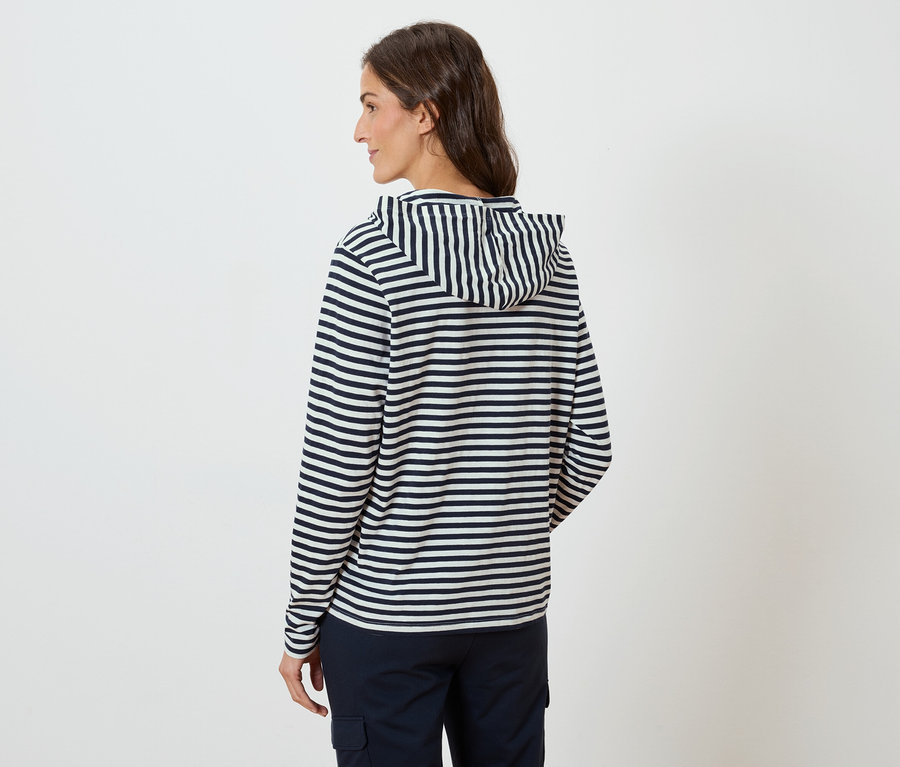 Hátulról látható nő, csíkos kapucnis pulóvert és sötétkék nadrágot visel.