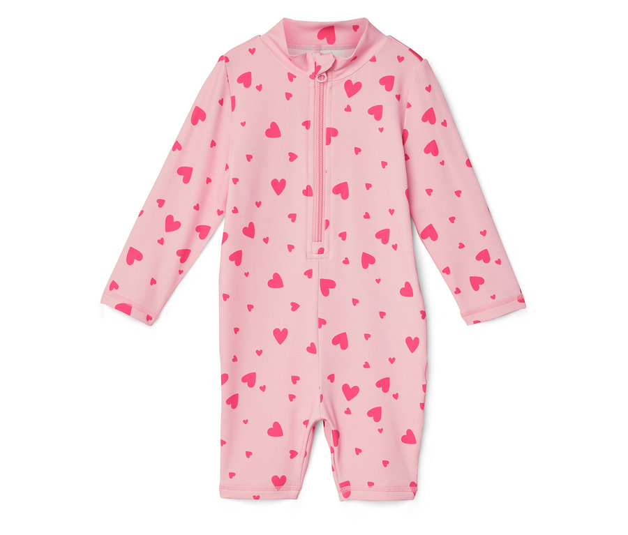 Egy világos rózsaszín, hosszú ujjú, teljes hosszában cipzáras fürdőruha piros szívekkel van nyomtatva.