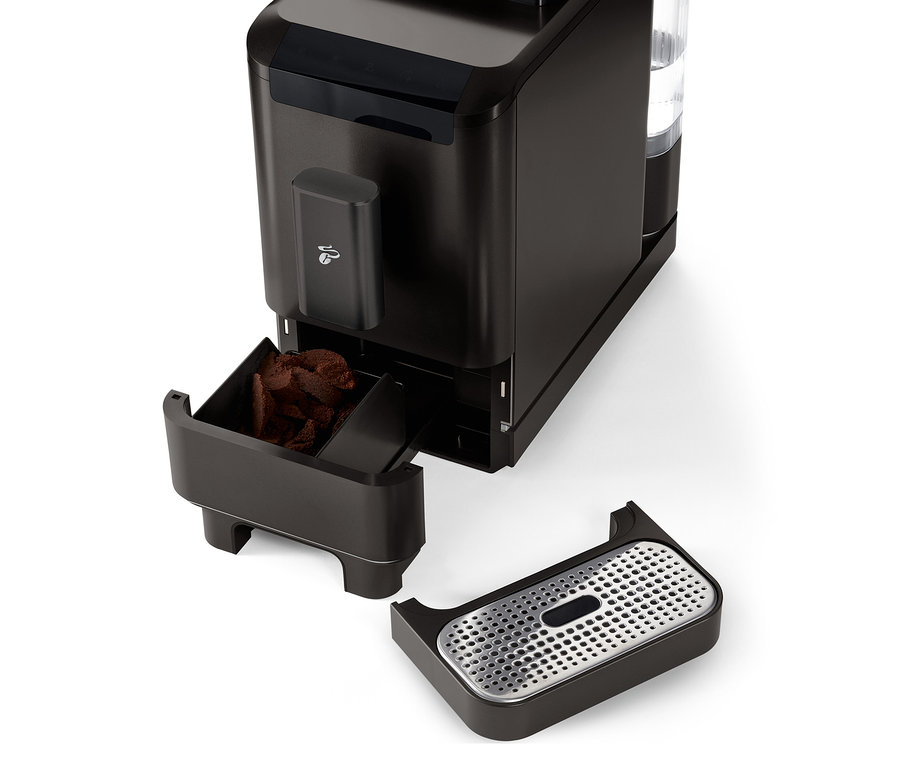 Közelkép a »Esperto2 Caffè« automata kávéfőzőről Granite Black színben, kihúzott kávézacc-tartállyal és csepptálcával.