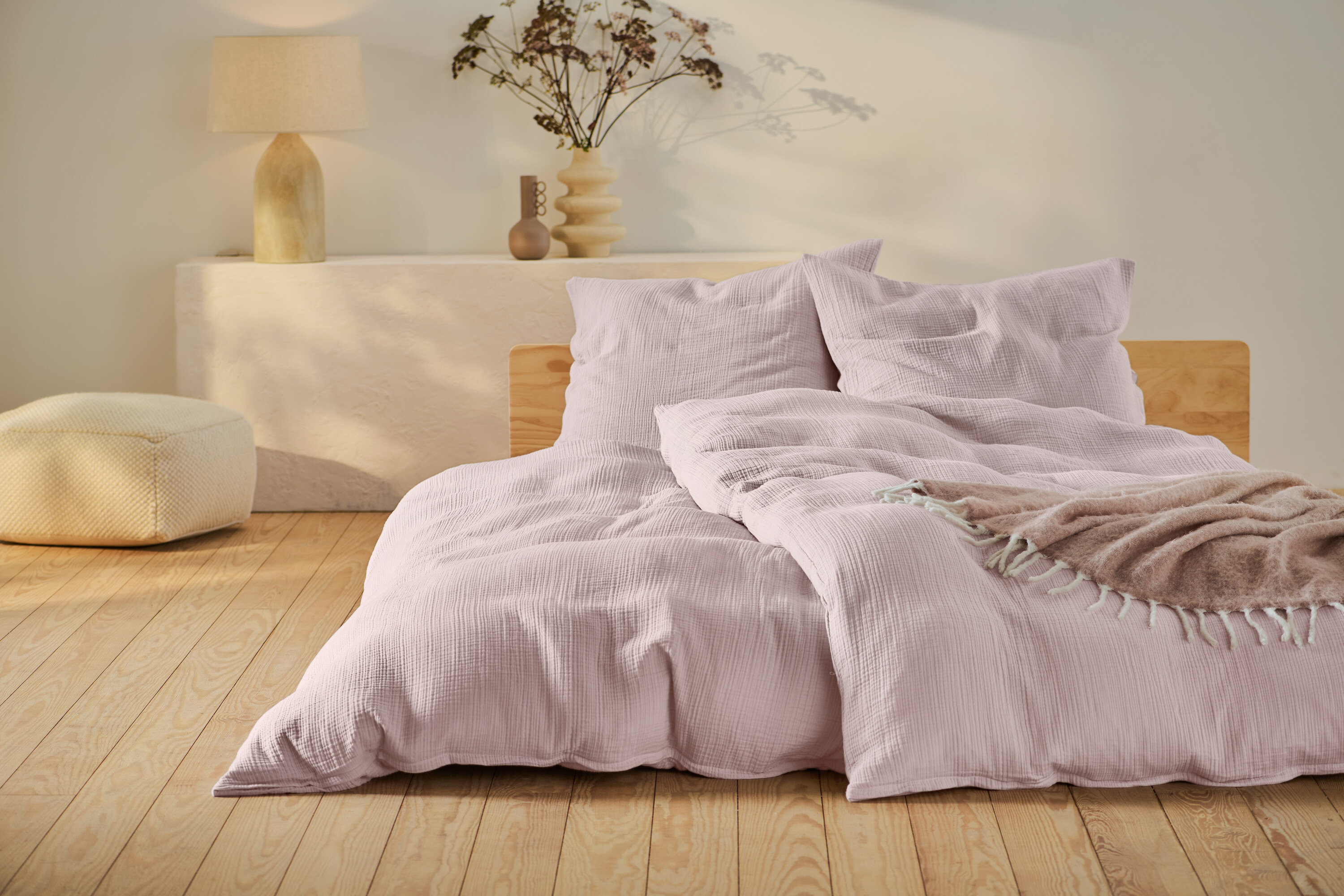 Rózsaszín muszlin ágynemű normál és extra méretben, fa keretes ágyon.