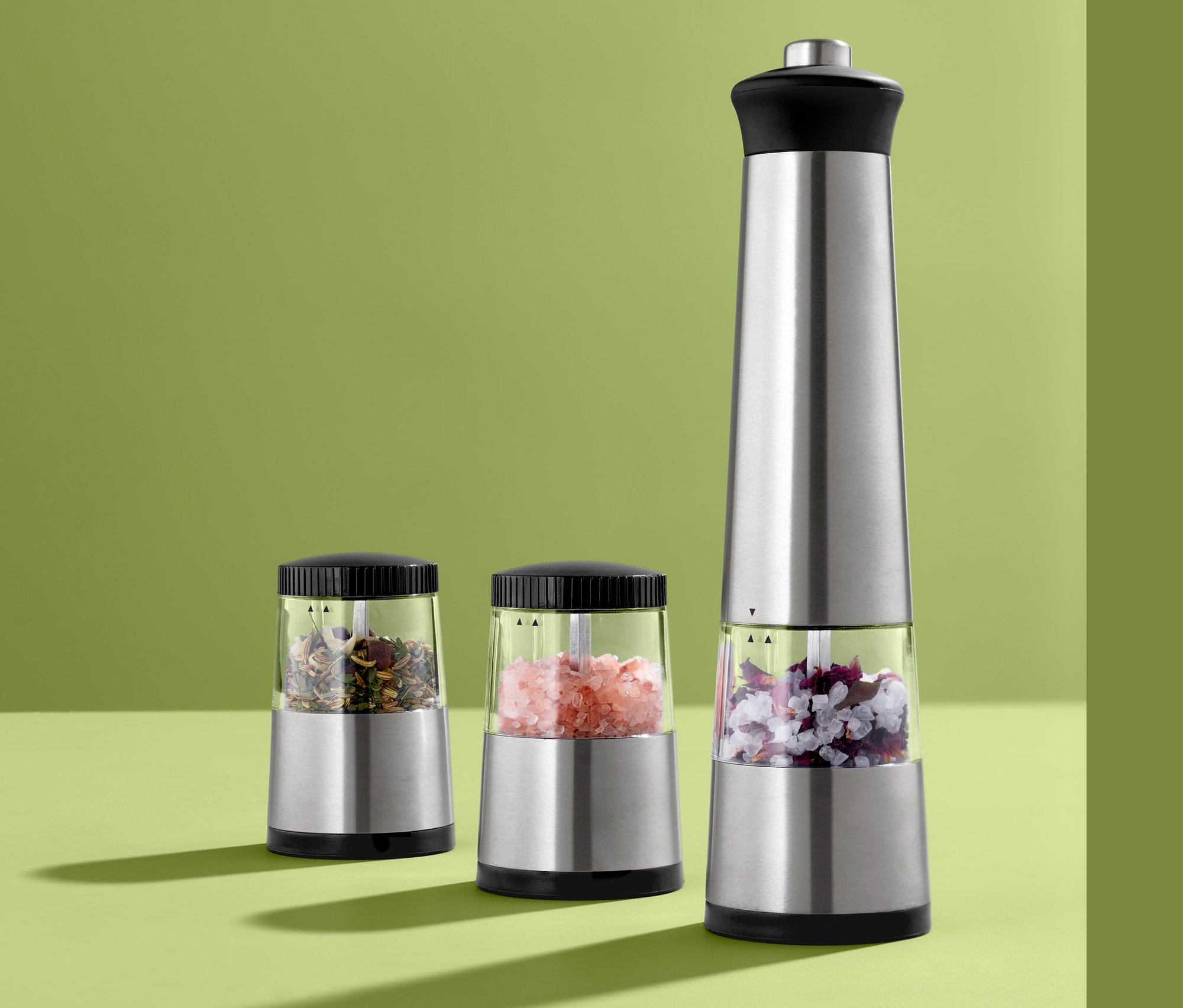 Három elektromos fűszermalom áll egy zöld felületen.