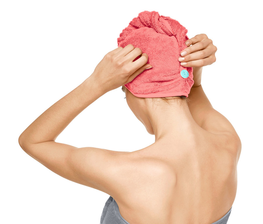 Nő turbán alakú törölközőt tesz a fejére.