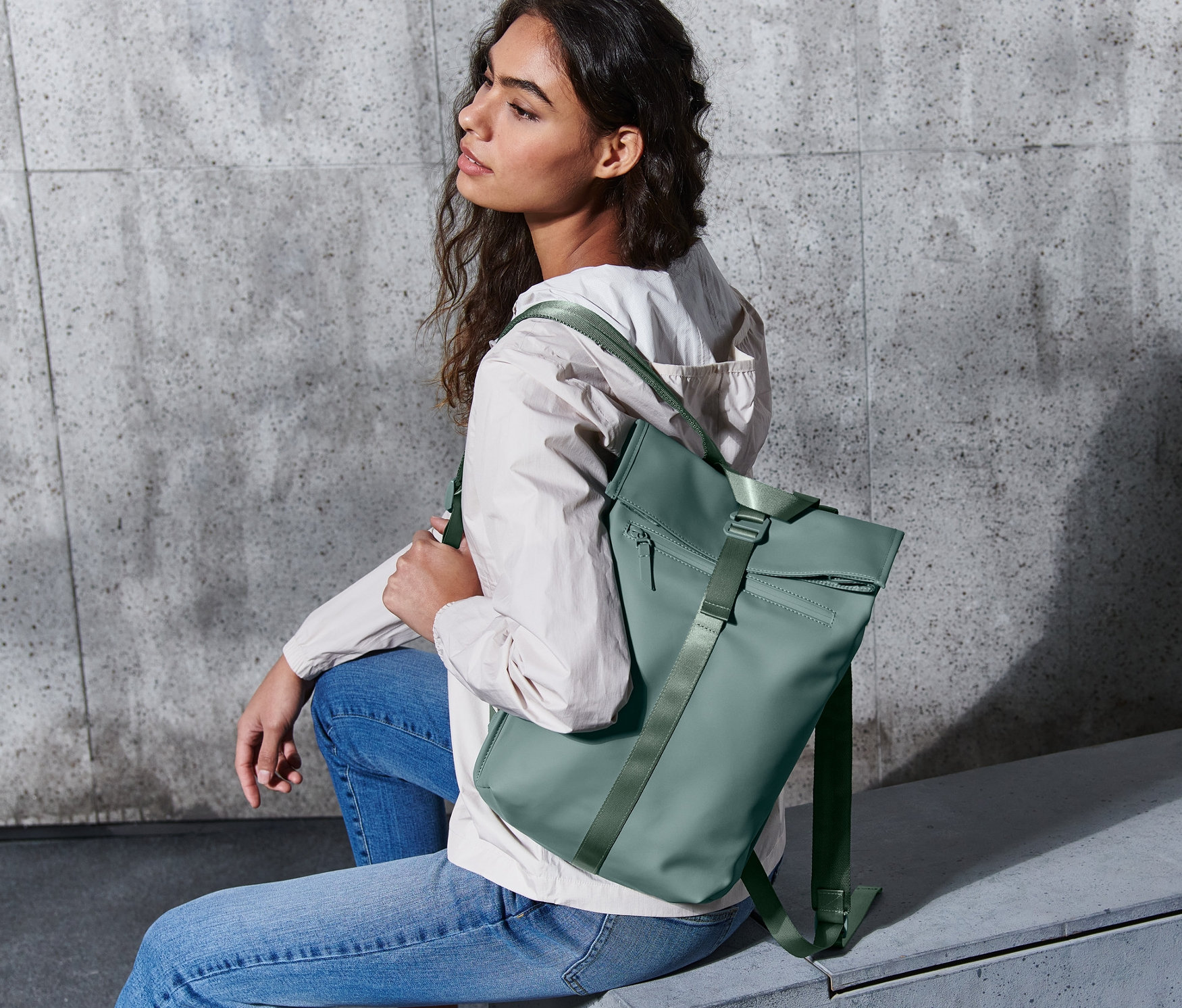 Nő ül egy hátizsákkal, víztaszító, zöld.