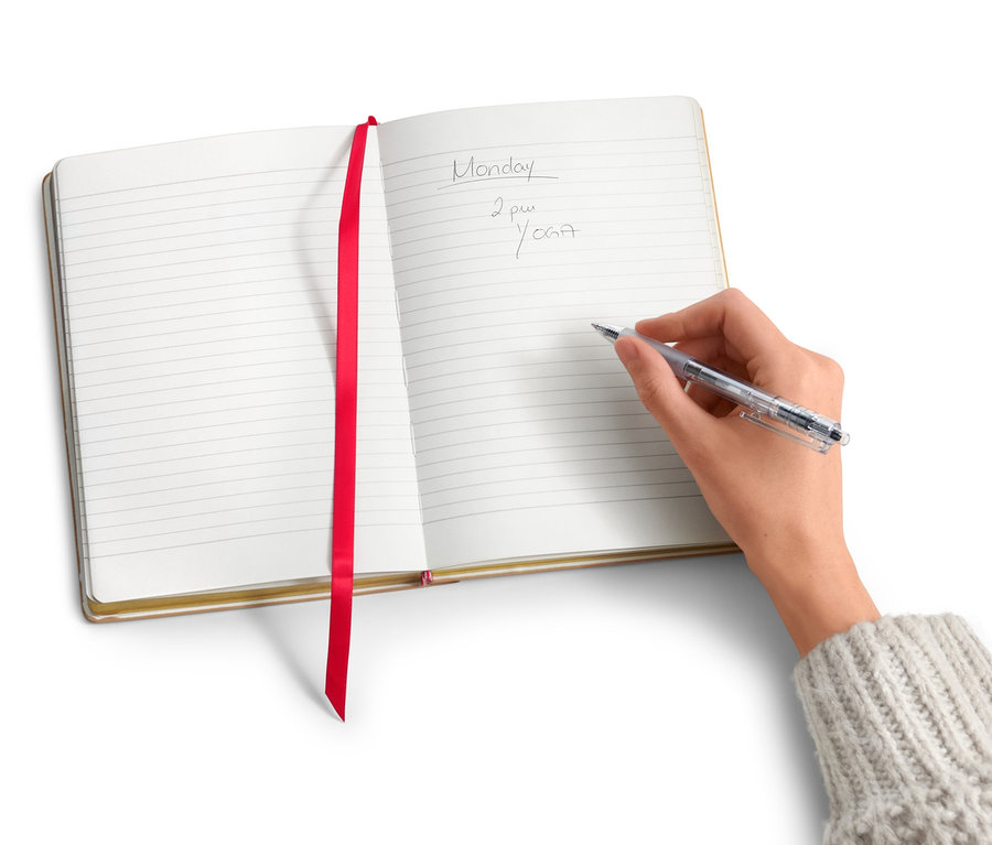 Egy kéz ír egy jegyzetfüzetbe.