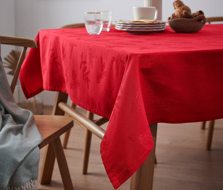 Piros jacquard asztalterítő egy fa asztalon az étkezőben.