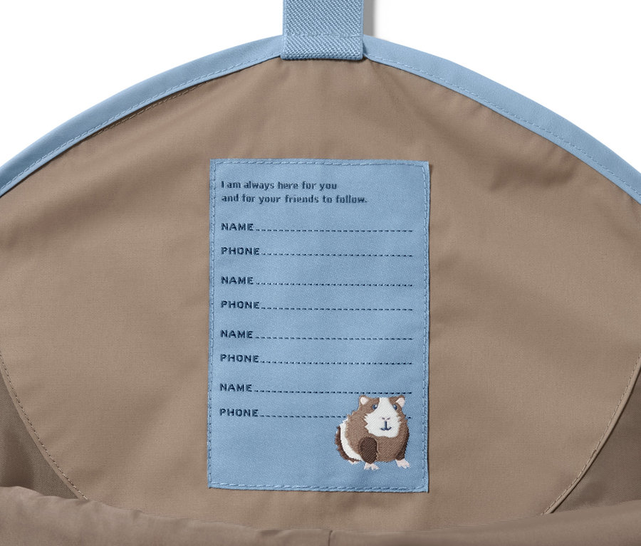 Egy táska belseje barna kisgyerek esőnadrággal és egy címkével, rajta használati utasítás.