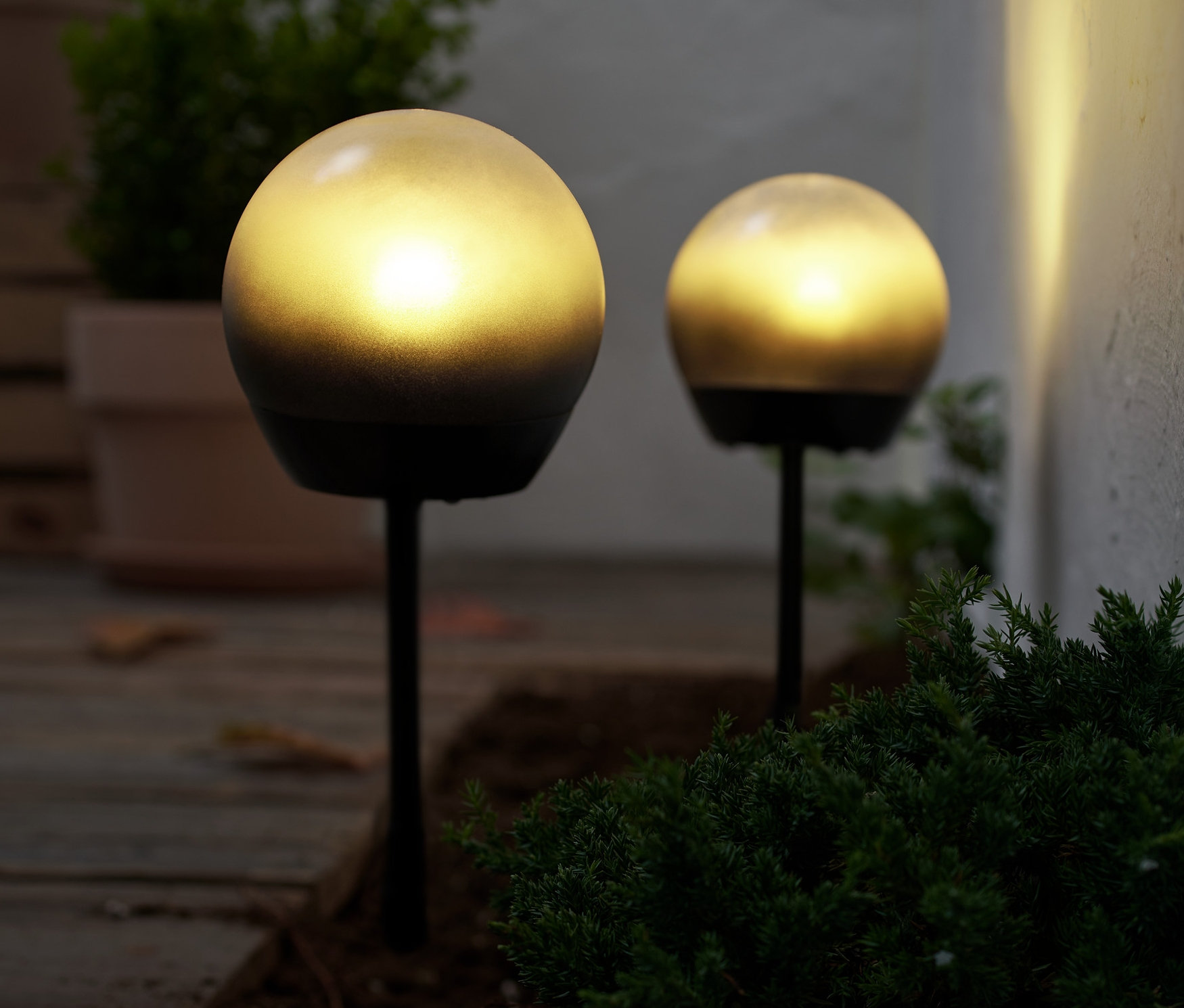 Két LED-es gömblámpa világítja meg a talajt a szabadban.