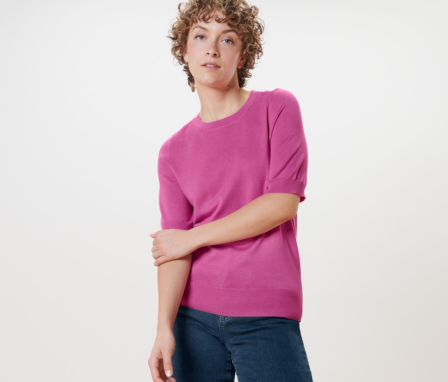 Nő pózol finomkötésű pulóverben.