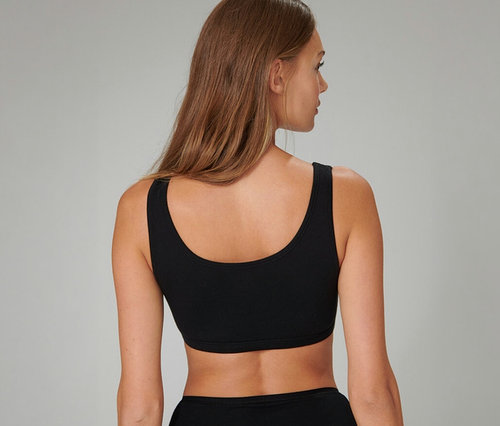 Hátulról látható nő hosszú barna hajjal, fekete SCHIESSER bustier melltartót és fekete alsóneműt visel.