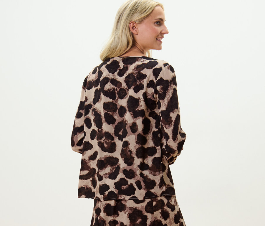 Szőke nő leopárdmintás női blúzban pózol.