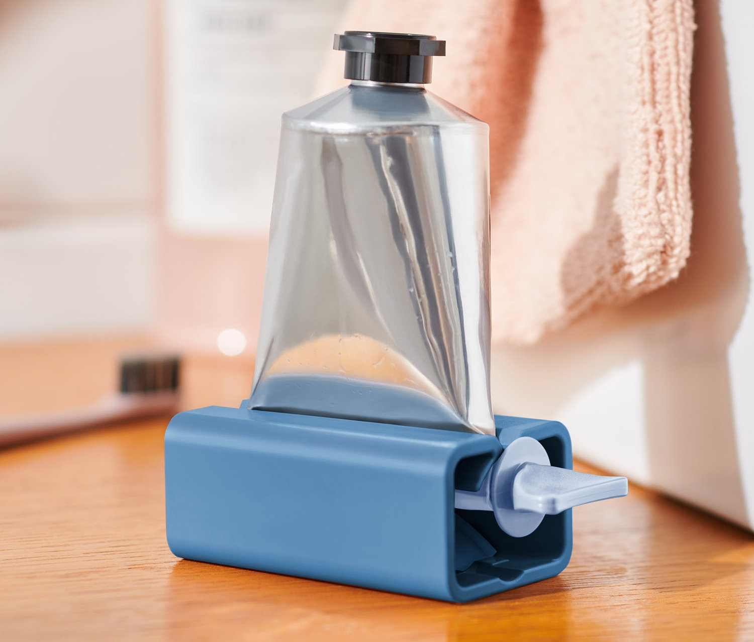 Ezüst tubus kék tubusnyomóban, fa asztalon.