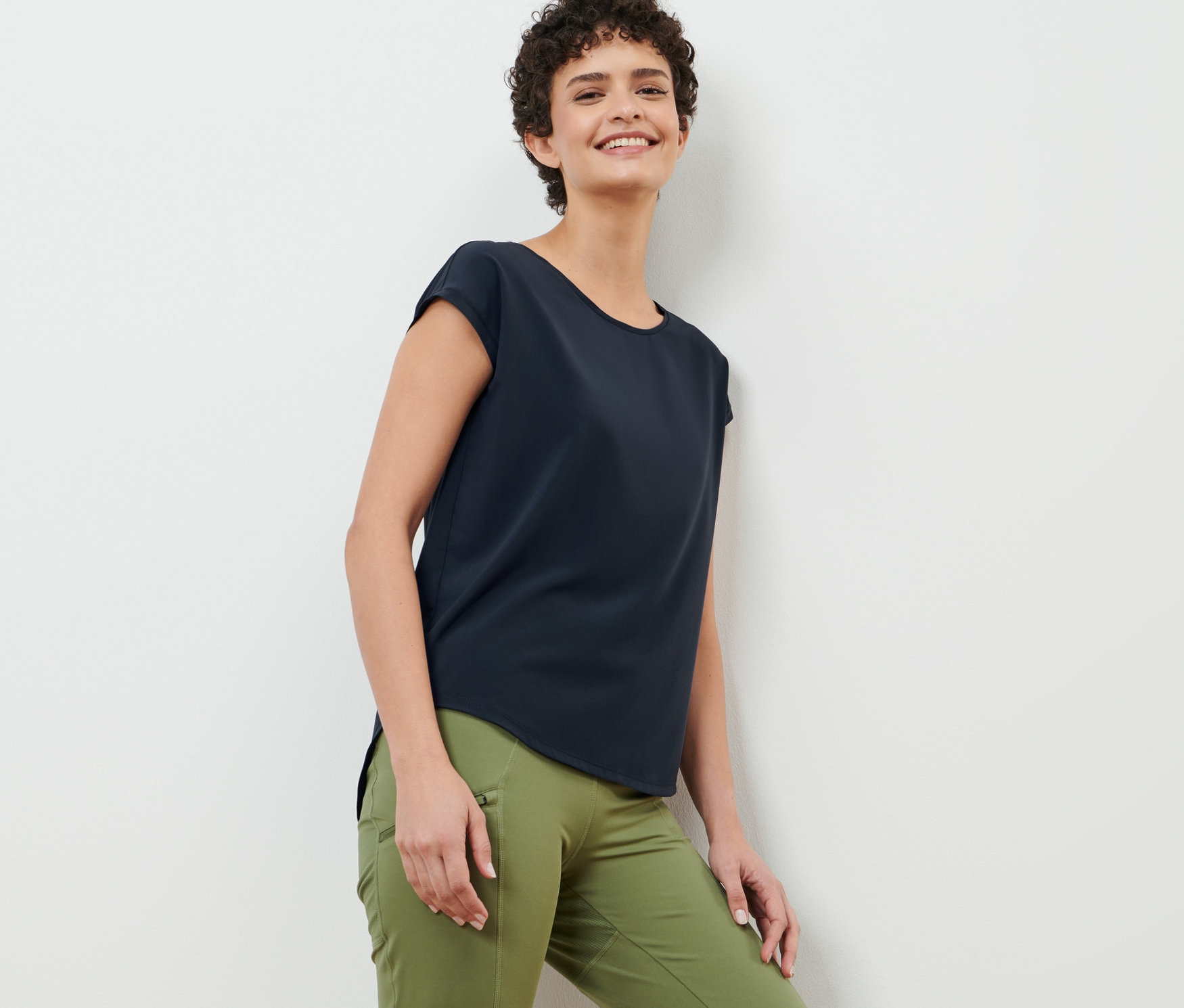 A falnak támaszkodó nő sötétkék sportfelsőt visel.