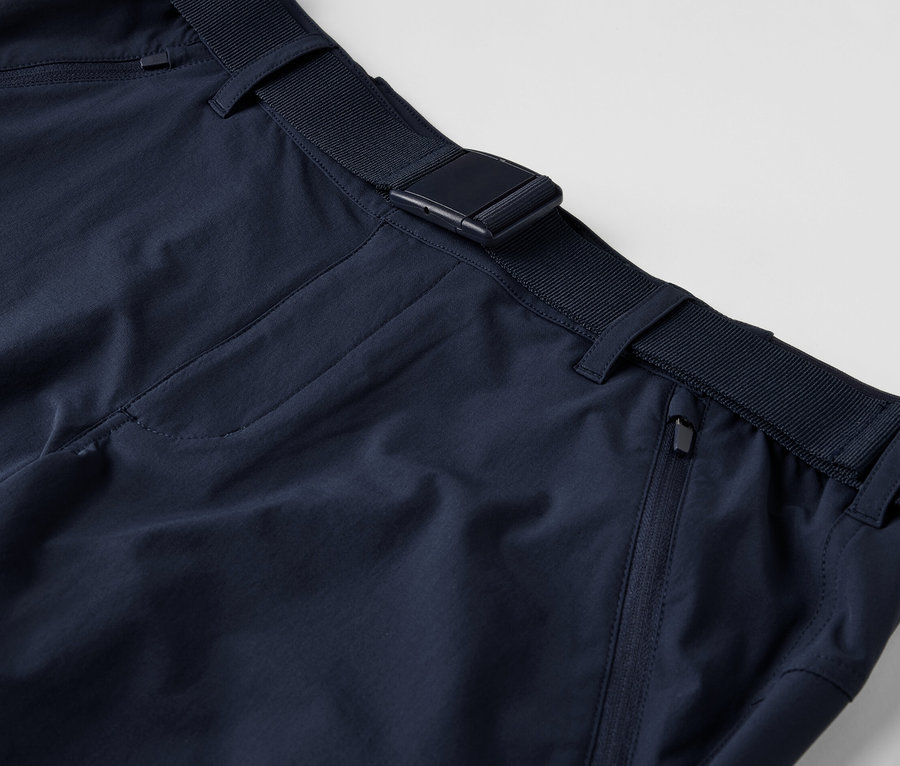 Egy sötétkék férfi túranadrág részlete övvel.