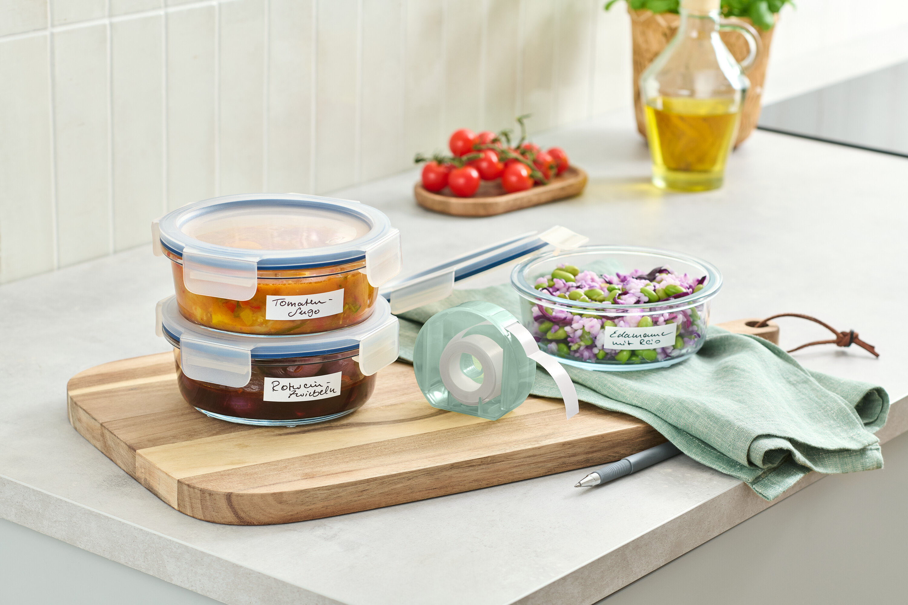 Két üvegtároló edény egymásra rakva egy fa deszkán egy címketekercs mellett.