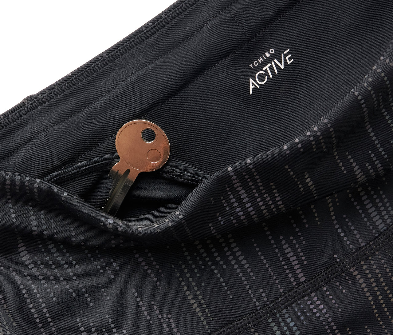 Egy fekete Tchibo Active leggings részlete, kulccsal a zsebében.