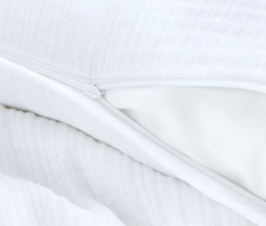 Egy fehér ágyneműhuzat részlete nyitott cipzárral.