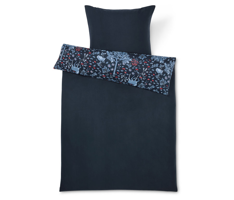 Sötétkék ágynemű párnával és díszpárnával, fákkal, virágokkal és állatokkal.
