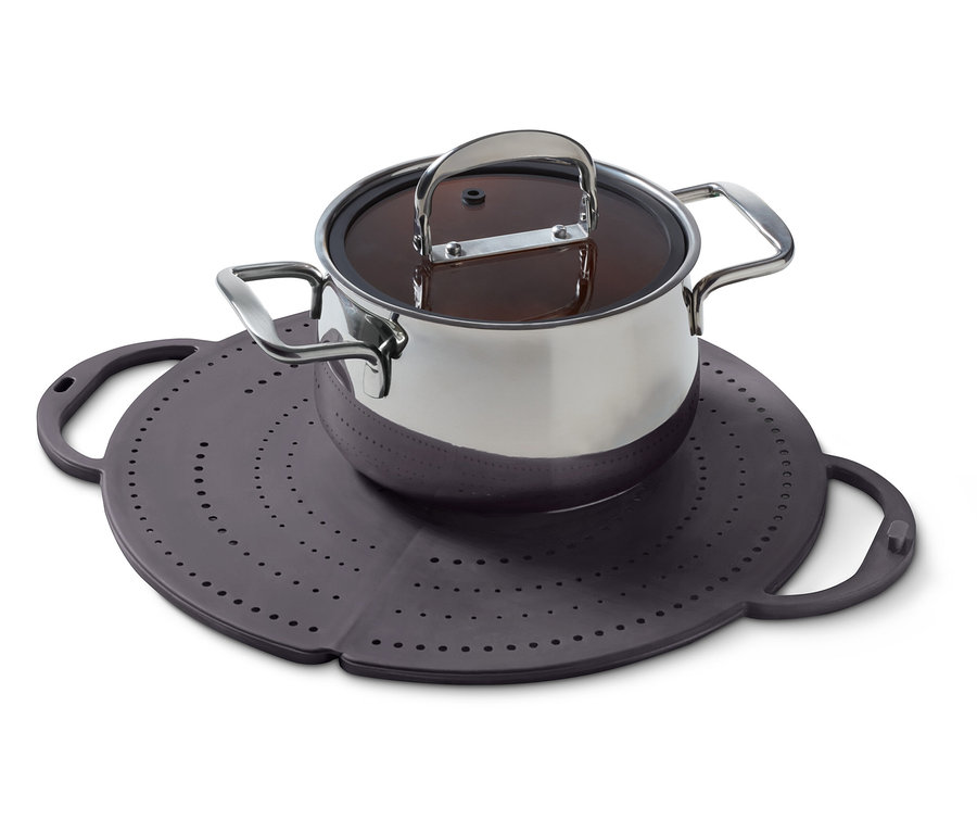 Egy rozsdamentes acélból készült edény fedővel egy lyukakkal ellátott lila szilikon alátéten áll.