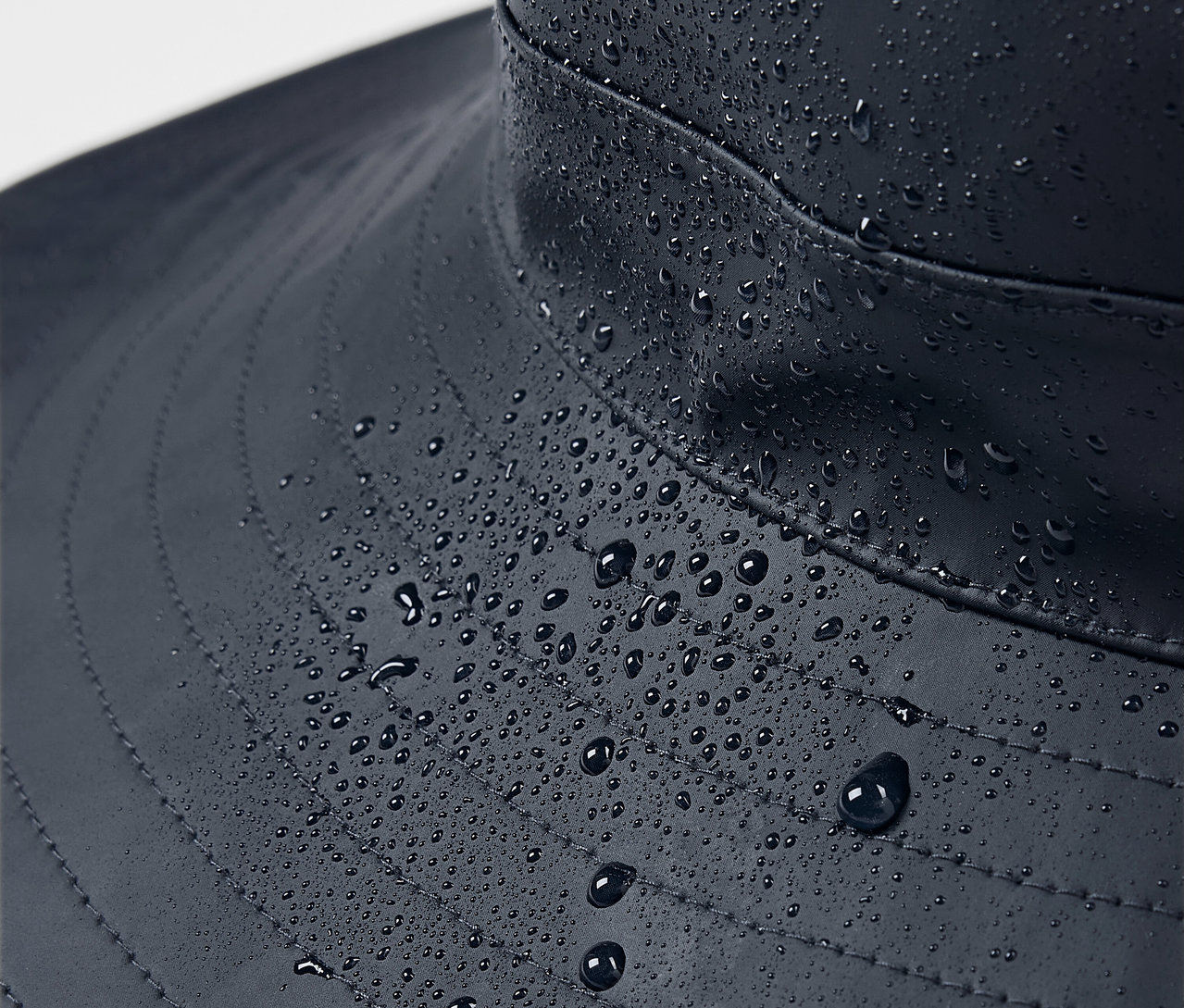 Kék esőkalap közelről, vízcseppekkel.