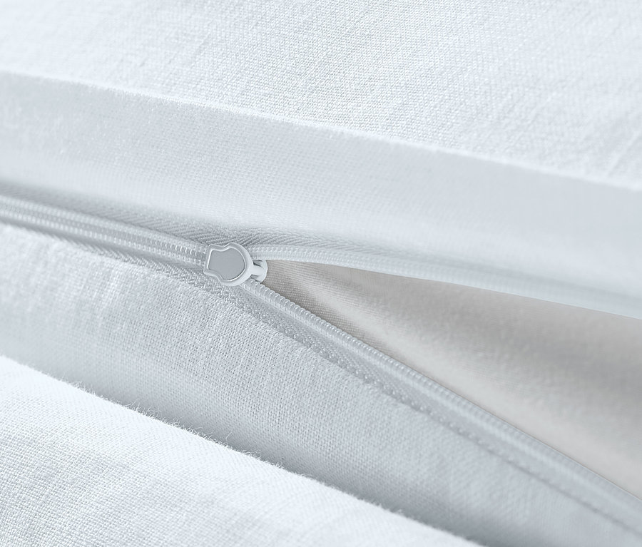 Egy fehér, extra méretű lenvászon ágynemű részlete cipzárral.