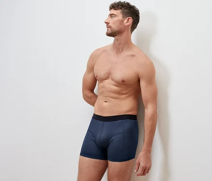 Férfi áll háttal, kék 2 sport boxeralsót visel.