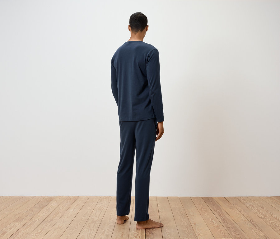 Egy férfi háttal a kamerának, sötétkék pizsamában.