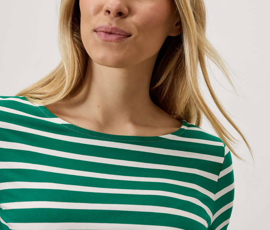 Szőke nő visel egy csíkos pólót.