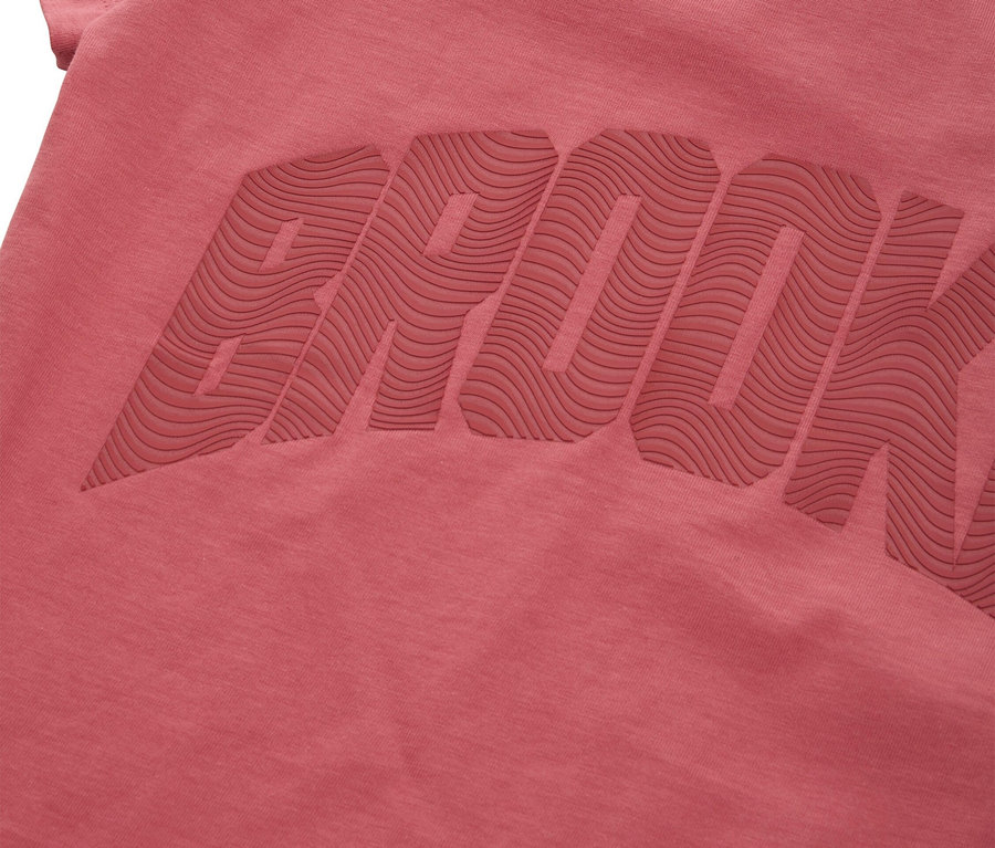 Egy rózsaszín póló közeli képe, amelyen a BROOK szó van dombornyomással.