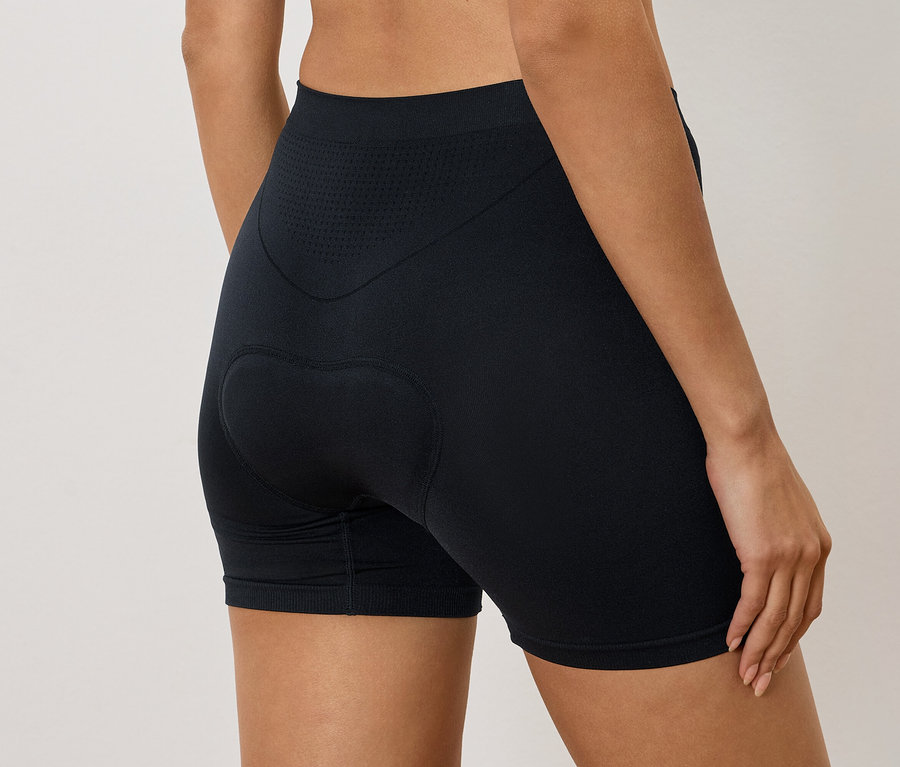 Nő visel fekete, párnázott kerékpáros rövidnadrágot, hátulnézet.