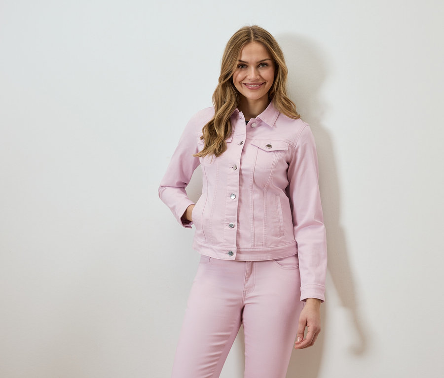 Nő visel rózsaszín farmerkabátot és hozzáillő farmert.