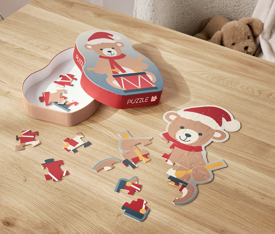 Egy Mikulás sapkás macis puzzle van szétszórva egy asztalon, mellette a doboza.