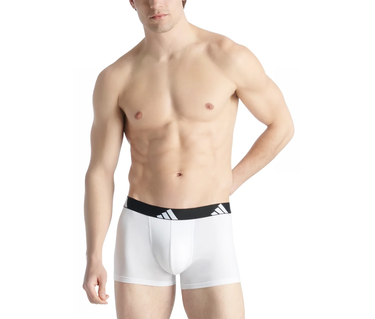 Felsőtestén meztelen férfi fehér boxeralsót visel, fekete derékpánttal és fehér Adidas logóval. Bal keze a csípőjén nyugszik.