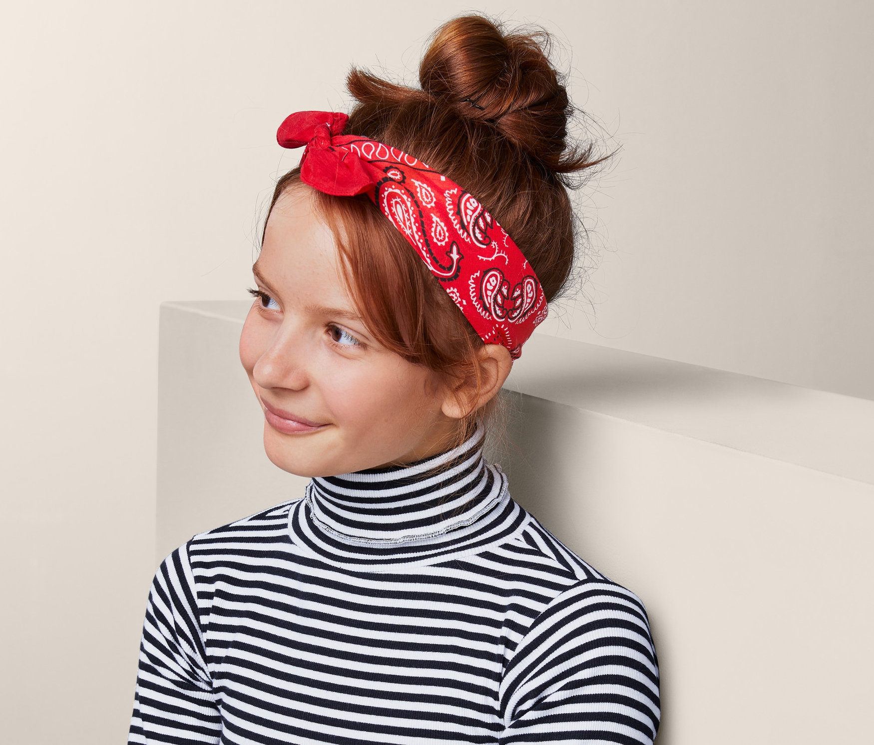 Egy lány piros, paisley mintás bandana szettből visel egy kendőt a hajában. Csíkos garbót és farmer szoknyát visel.