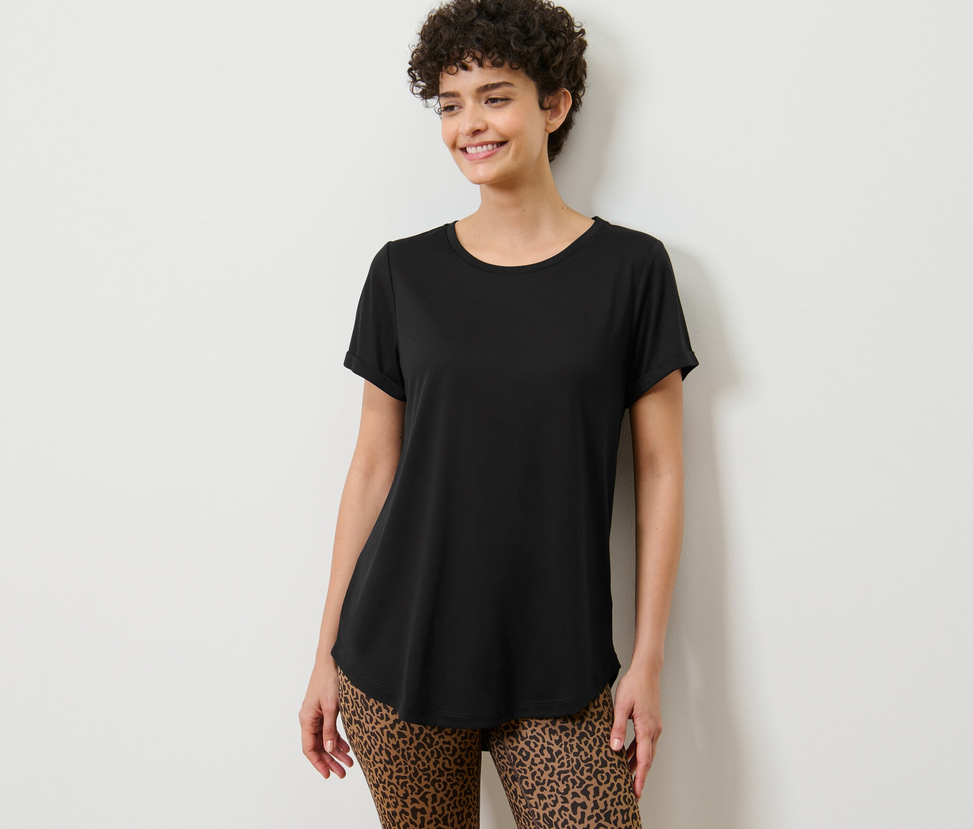 Nő pózol egy fekete hosszú felsőben.